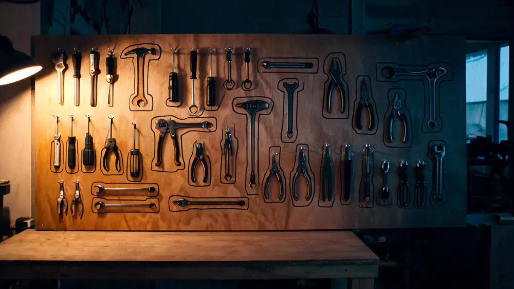 A workshop shadow board at the end of a day, every hand tool hung back inside its own painted outline.